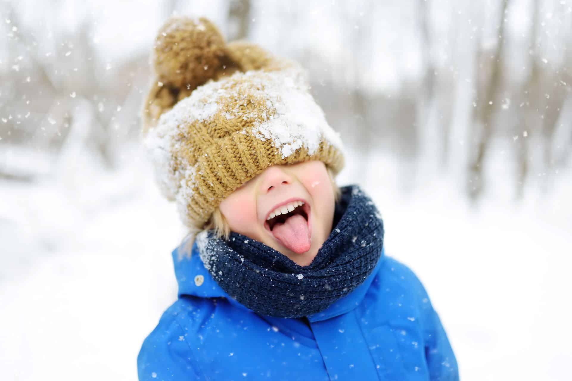 Kind mit Mütze spielt im Schnee